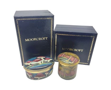 Two Moorcroft enamel boxes, the first example of oval form, decorated with mushrooms upon a blue ground, the second of circul
