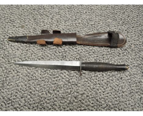 A British WWII Fairburn Sykes Commando Knife, blade length 17.5cm, overall length 29cm, with leather scabbard