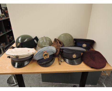 A collection of Military Caps and Helmets including South Africa Police Equestrian Helmet, South Africa Police Helmet with a 