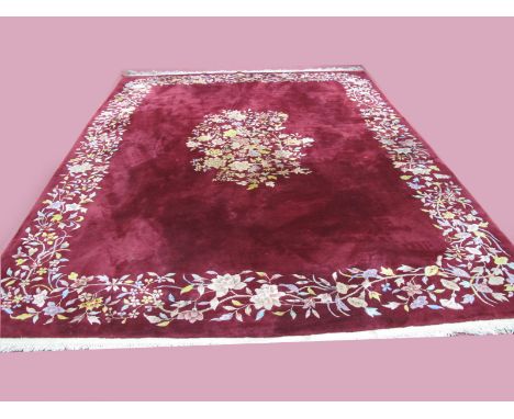 A Tasseled Wool Carpet, circa mid XX Century, with floral centre and border on maroon ground, 364 x 270cm.