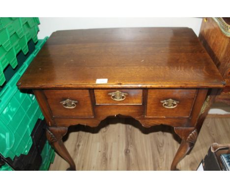 AN ANTIQUE OAK THREE DRAW TABLE WITH DECORATIVE BRASS HANDLES