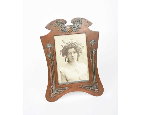 An Art Nouveau easel back patinated copper picture frame, shaped, rectangular form applied with Art Nouveau maiden and tall f