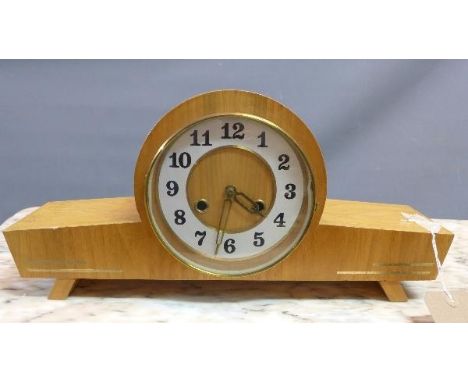 An oak veneered 1950's Art Deco style mantel clock, the white chapter ring with Arabic numerals on splayed block feet. 