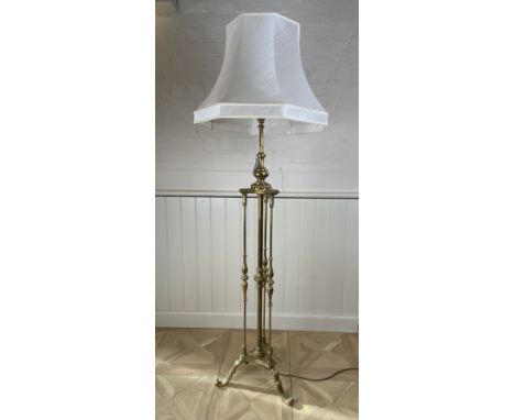 A brass standard lamp On turned support on a tripartite base with scroll feet, together with a cream silk shade, fitted for e