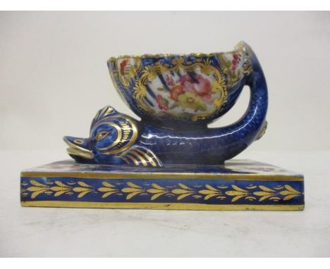 A mid 19th century inkwell and pen stand fashioned as a shell on the back of a fish, on a plinth, decorated with flower carto