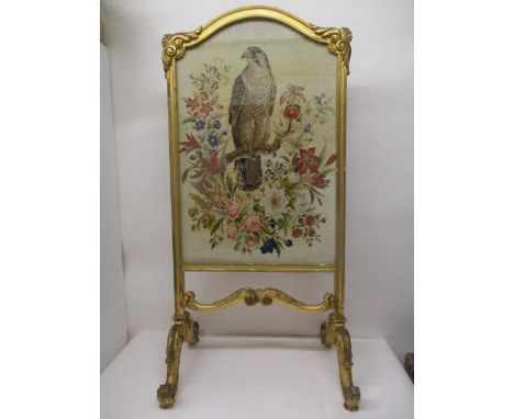 A late 19th century gilt gesso and carved firescreen with an arched top, scrolled ornament and an embroidered panel depicting