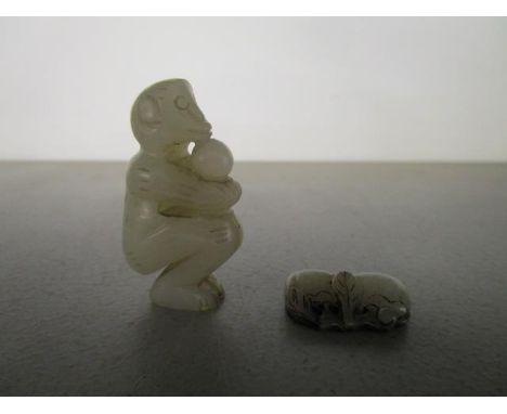 Two Chinese pale green jade carvings, probably 19th century, one a monkey squatting, holding a single fruit, 2" h, the other 