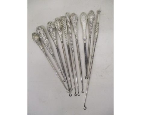 Ten Victorian and later silver and white metal handled, large button hooks, each with embossed decoration 