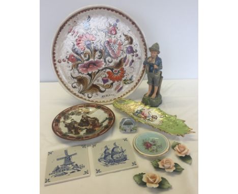 A box of assorted ceramic items. To include Capodimonte flowers, large floral hand painted charger & continental figurine of 