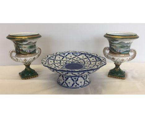 A pair of  Dresden style ceramic two handled urns, together with an oriental ceramic comport. Urns depict painted landscape s