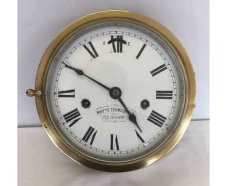 A vintage brass bulkhead clock with enamel dial. Marked Whyte, Thomson & Co., Glasgow. Dial made in France. Mounted on wooden