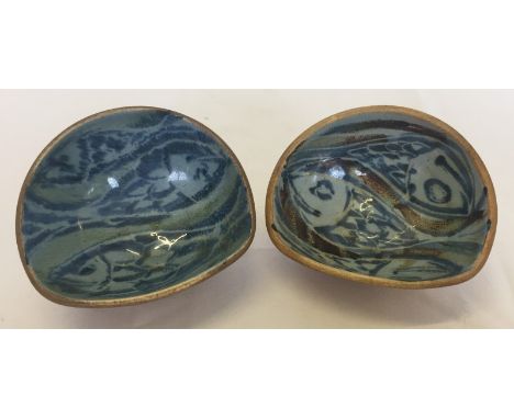 A pair of Arch, St. Ives, studio pottery 3 footed dishes. Painted with fish decoration. Each approx 12x10cm, and 7cm tall.