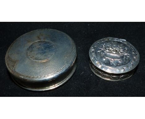 A silver engine turned circular patch box; a floral embossed patch box