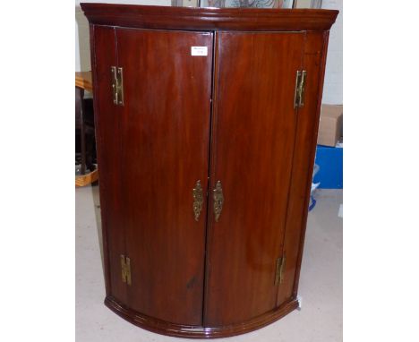 A Georgian mahogany bow front corner cupboard with moulded cornice and 2 doors