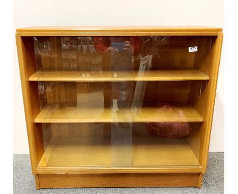 A 1970's light oak bookcase with sliding glass doors, W. 91cm H. 84cm.