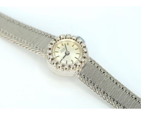 18 K Weißgold, gestempelt. Rundes Gehäuse flankiert von 18 kleinen Diamanten von zus. ca. 0,27 ct, TWvsi 1. Glänzendes Ziffer