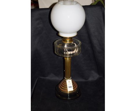 A Victorian brass oil lamp with opaque shade and clear glass reservoir, raised on a reeded column.