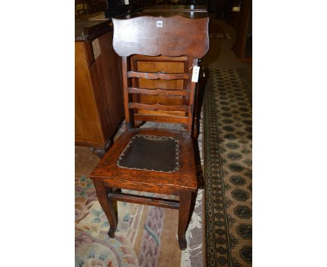 An early 20th Century Arts & Crafts oak ladder back chair, with leather-cloth covered seat, 99cms high.