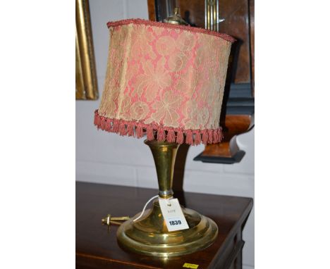 An early 20th Century brass table lamp, with lace covered shade.