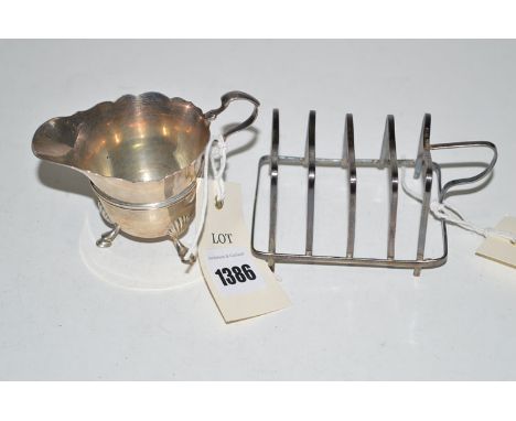 A silver five bar toast rack, by T. & J.H., London 1975; together with a helmet form cream jug, London 1900.  (2)