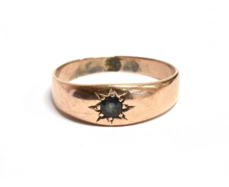 A YELLOW METAL STAR GEM SET GYPSY RING The ring set with a dark blue sapphire on an unmarked yellow shank, gem diameter 0.4cm