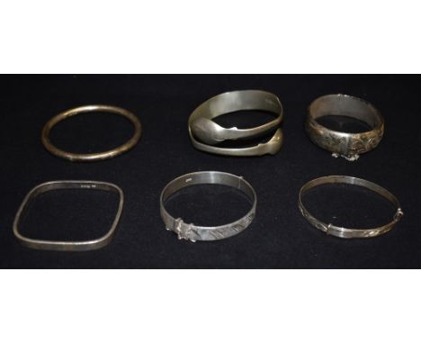 A COLLECTION OF FOUR SILVER BANGLES  together with a plated spoon bangle and an unmarked white metal expanding bracelet