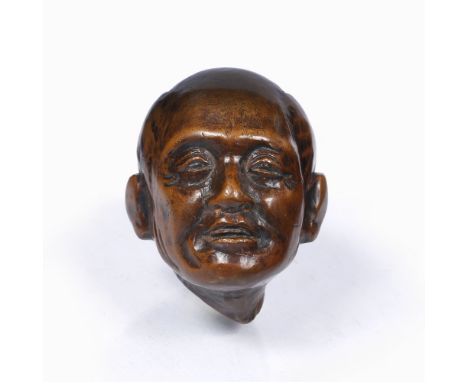 A Japanese wood netsuke 19th Century carved as a severed adult male head with a contemplative expression