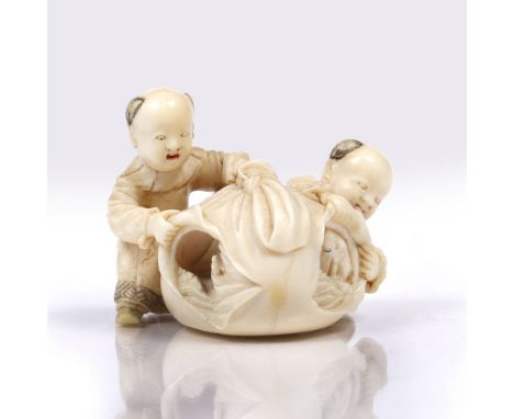 A Japanese okimono of two boys playing with a sack late Meiji opening to reveal a landscape