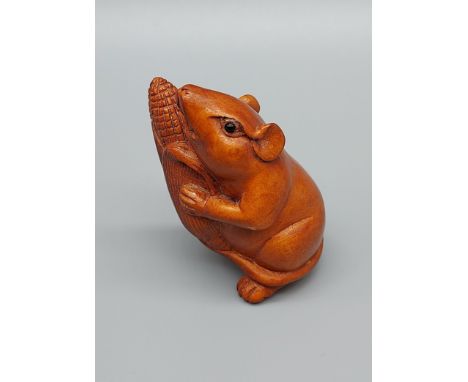 A Japanese hand carved netsuke of a mouse holding a corn. Signed. [4.5cm in height] 