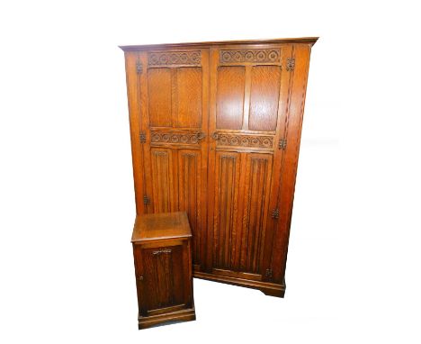 An Inglesants oak double wardrobe, with a pair of linen fold and carved panel doors, opening to reveal a shelf and two rails,