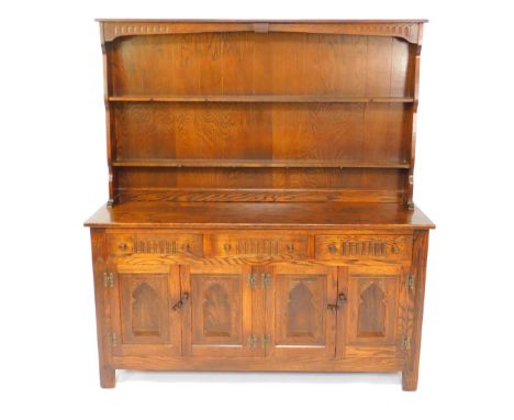 A Webber Croydon Range oak dresser, the two shelf plate rack over three carved drawers over four panelled doors, raised on sq