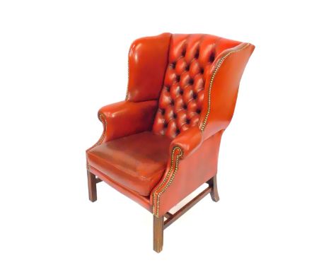 An oak framed red leather button back wing armchair, with loose cushion seat, and brass stud work, raised on fluted square le