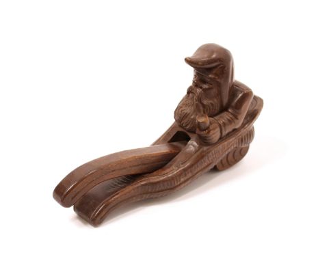 Nutcrackers - a Black Forest lever-action novelty nut cracker, carved as a gnome, seated, holding a glass, 23cm long, early 2