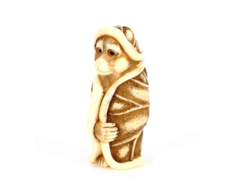 A finely carved Japanese ivory Netsuke, depicting a standing monkey wearing a lily pad hat and gown, with signature, 5cm high