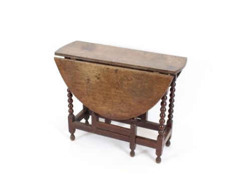 An 18th Century oak gate leg table, with rounded drop leaves, raised on barley twist supports, 88cm