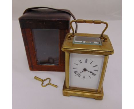 A brass carriage clock of customary form with white enamel dial and Roman numerals in original leather bound carrying case, w