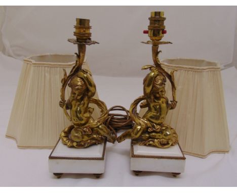 A pair of late 19th century continental ormolu putti supporting light fittings on square marble bases with silk shades, 42cm 