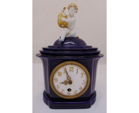 An early 20th Century KPM Berlin porcelain mantel clock with putti finial, the clock body having assimilated columns and a co