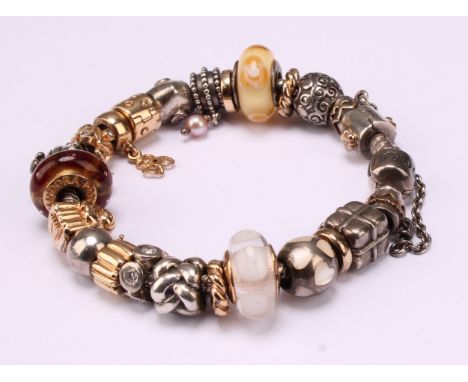 A Pandora charm bracelet, with twenty three 14ct gold, silver and silver gilt charms including angel, heart ball, wrapped Chr