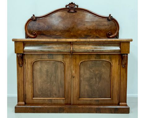 An early Victorian mahogany chiffonier, shaped quarter galleried back, with carved crest, and C-scroll terminals, above a sli