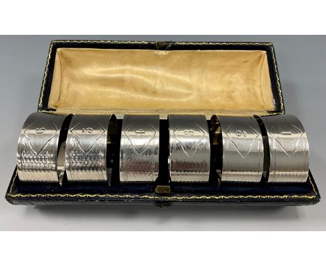 A Victorian cased set of six silver napkin rings, engine turned scaled bands with shaped cartouche numbered 1 to 6, Atkin Bro