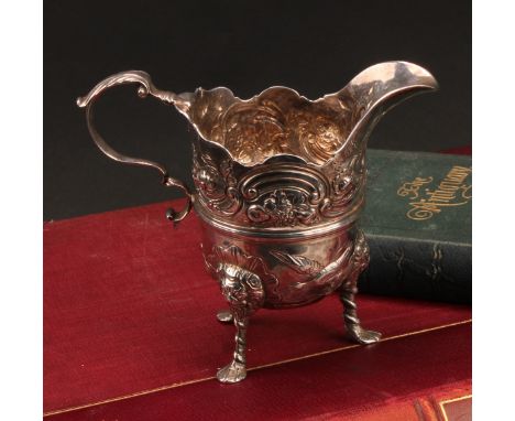 An 18th century Irish silver cream jug, of bold design, chased with ducks taking to flight, flowers, fruit and C-scrolls, aca