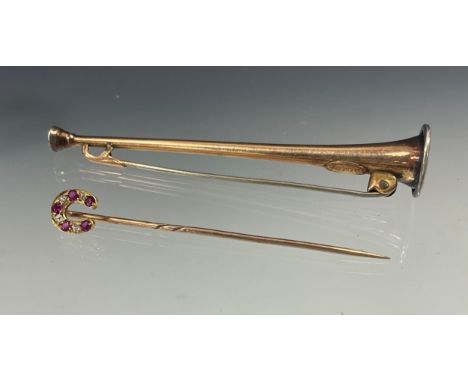A diamond and ruby horseshoe topped tie pin, unmarked yellow metal mount, with nine alternating rose cut diamonds and five pi