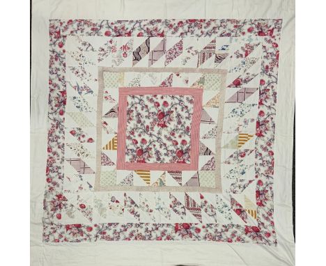 A late 19th/early 20th century patchwork quilt, with floral centre, surrounded by triangular and square sections predominantl