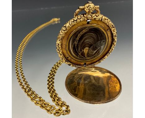 A Victorian yellow metal mourning locket, engine turned and floral decoration, the interior with hair and wire work panel, un