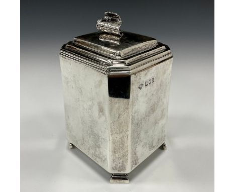 An Art Deco silver tea caddy, stepped hinged cover with curled leaf handle, plain canted square body, tapering feet, 13.3cm h