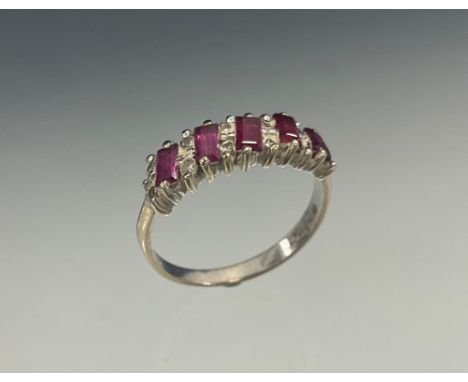 A ruby and diamond ring, set with alternating rows of pale pink baguette cut rubies and pairs of round brilliant cut diamonds
