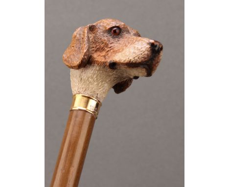 An early 20th century walking stick or cane, by Brigg, the handle carved as the head of a hound dog, gold coloured metal coll