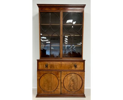 A Regency mahogany secretaire bookcase, the outswept cornice with Kingwood banding, over a pair of astral-glazed doors, enclo