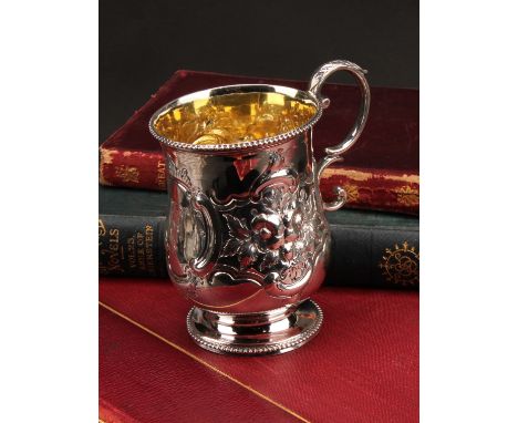 A Victorian silver pedestal mug, chased with scrolls, flowers and foliage, acanthus-capped double scroll handle, gilt interio